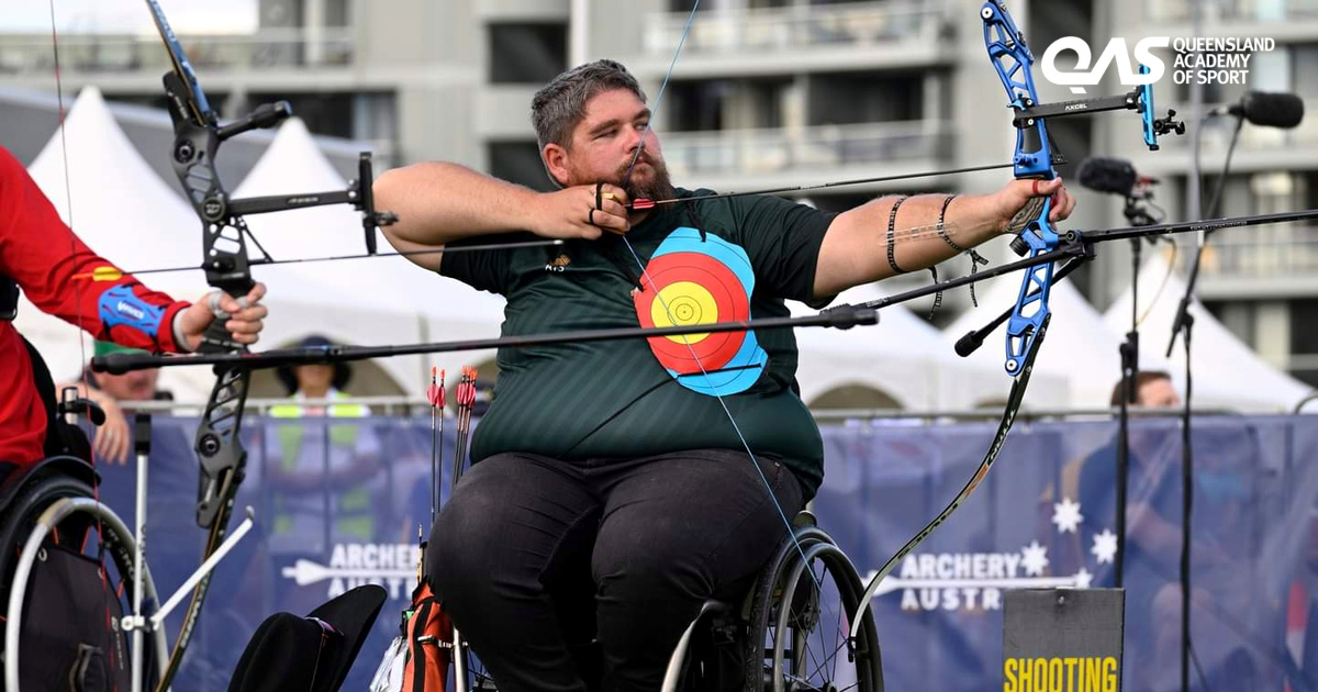 Thomas Holland at full draw, competing in recurve archery from his wheelchair